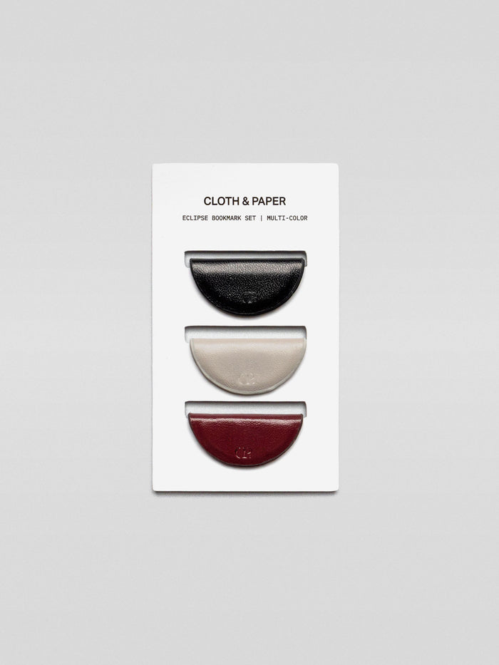 A set of three semi-circle leather magnetic bookmarks in black, cream, and burgundy colors, displayed on a branded Cloth & Paper card.
