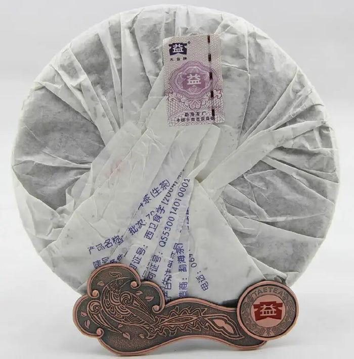 Wrapped puerh tea cake with Chinese label on a decorative metal tea stand