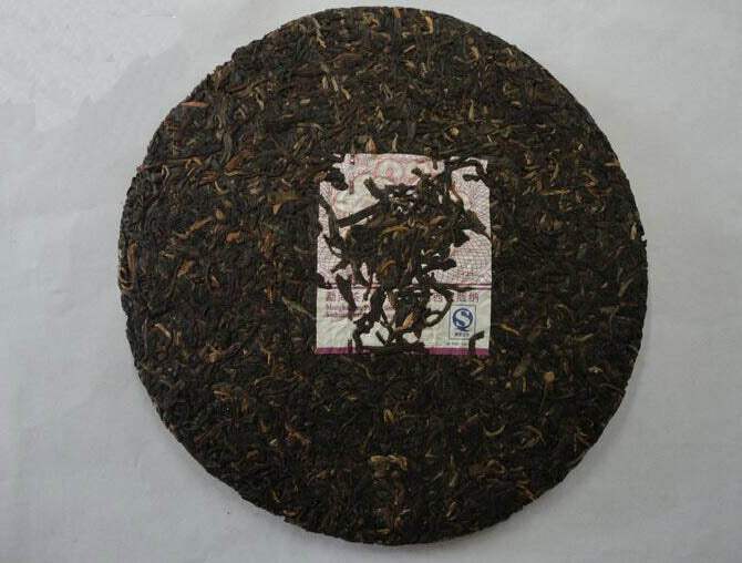 Compressed Chinese puerh tea cake with visible tea leaves and central label on white background