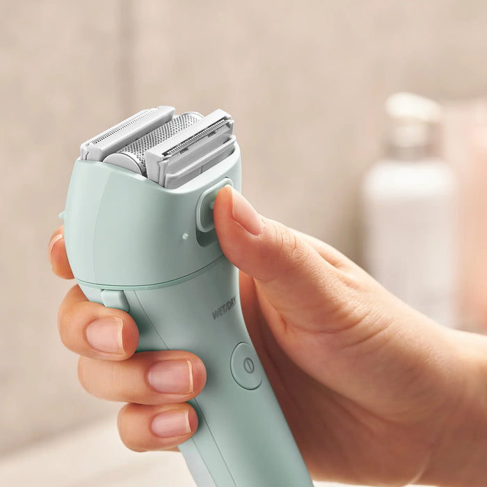 Woman holding 3-Blade Women's Electric Shaver (ES-WL60-G) with ultra-sharp floating blades and pop-up bikini trimmer for gentle and precise shaving.