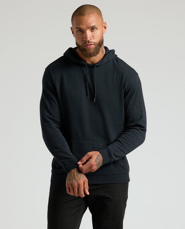 Model wearing All Black Classic Waffle Hoodie, showing kangaroo pocket and drawcords.