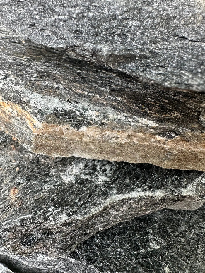 Black slate stone with rough dark gray surface and brownish speckled edge