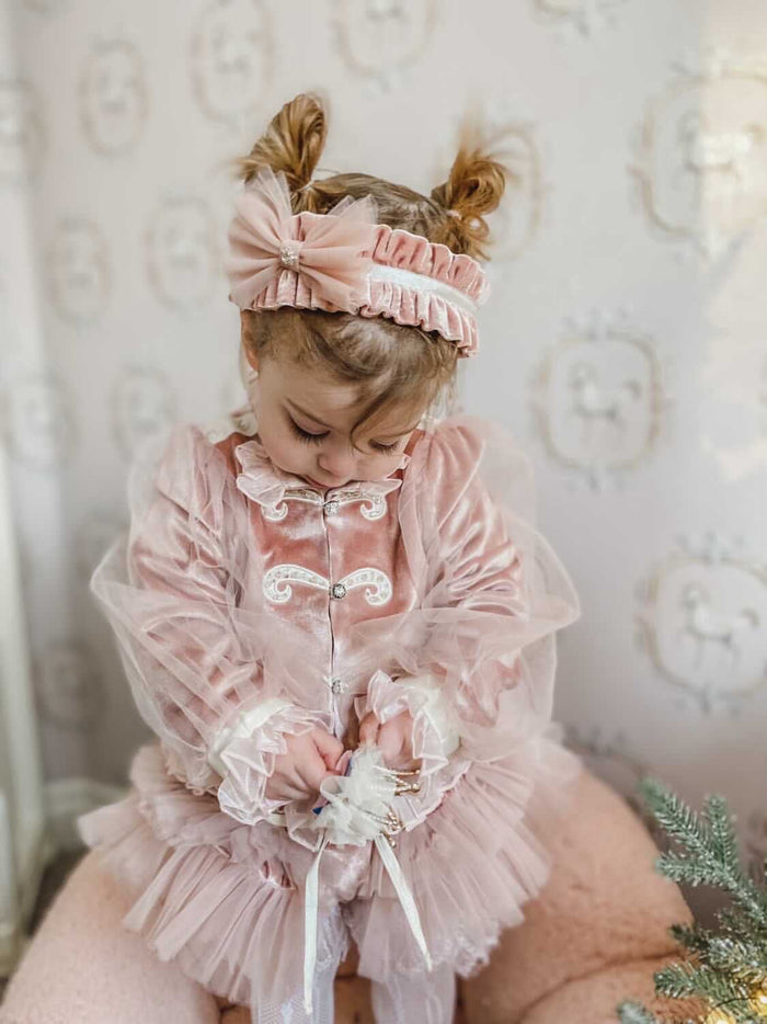 Toddler girl wearing Clara Pink Velour Jacket and Bloomers Set with pink ruffle headband, sheer puff sleeves, and layered tutu-style bloomers.