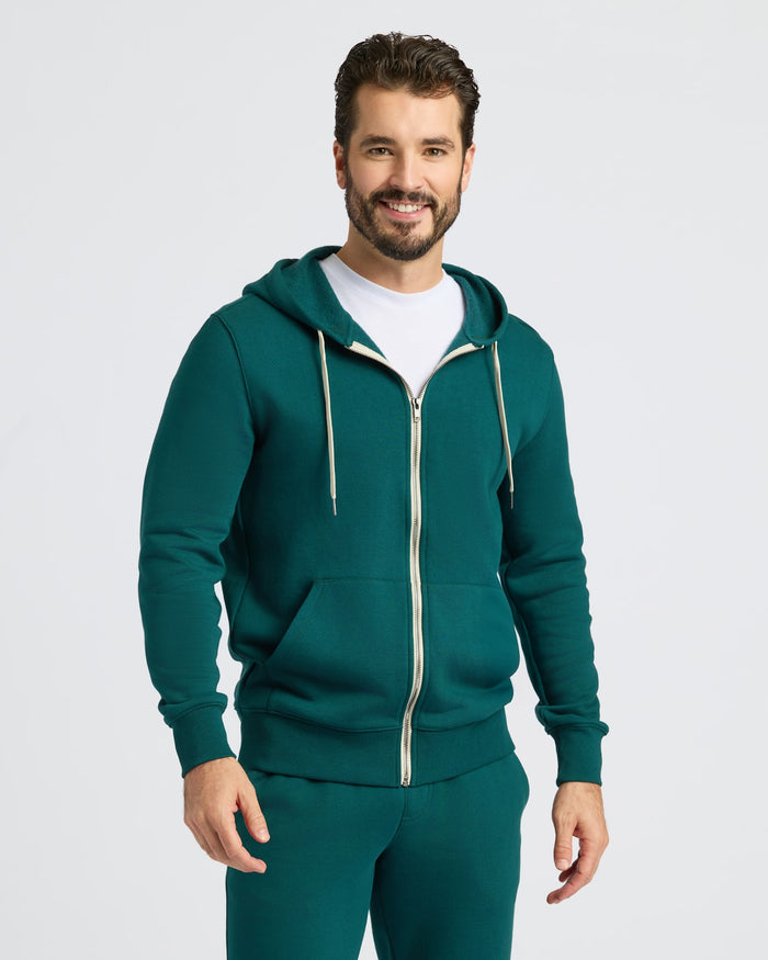 Man in Deep Emerald Fleece French Terry Zip Hoodie, smiling slightly.