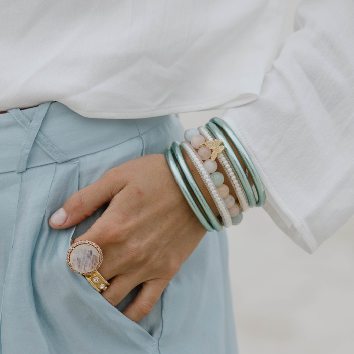 a hand with bracelets and a ring on it