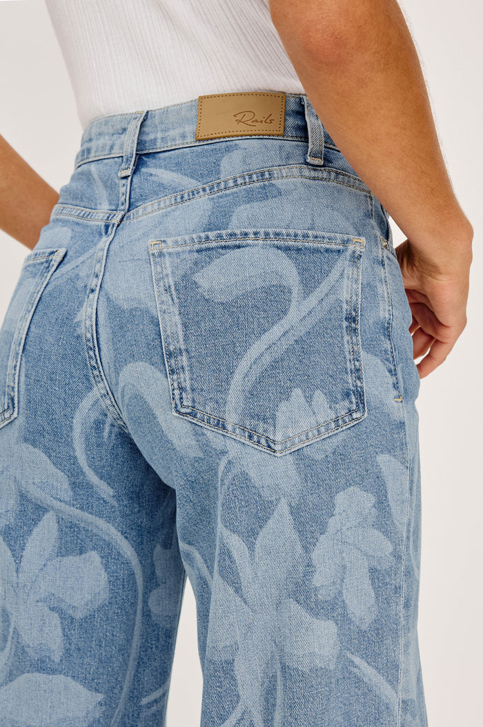 Getty Wide Leg Jean in Light Stretch Denim With High-Rise High-Waisted Fit, Button Fly, and 5-Pocket Styling in Floral Laser Colorway - Lower Body Back Close Up View Featured on Model
