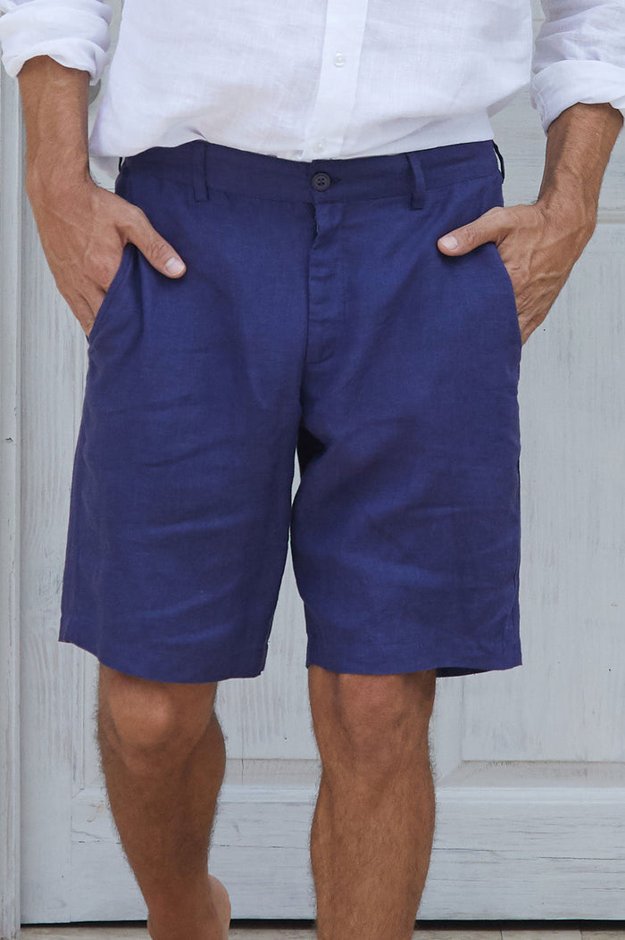 Man wearing tailored navy linen shorts with side pockets, paired with a white button-up shirt.