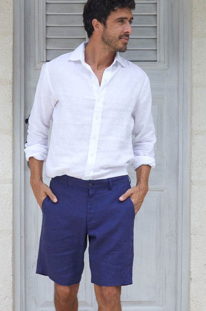 Man wearing navy linen tailored shorts, paired with a white button-down shirt.