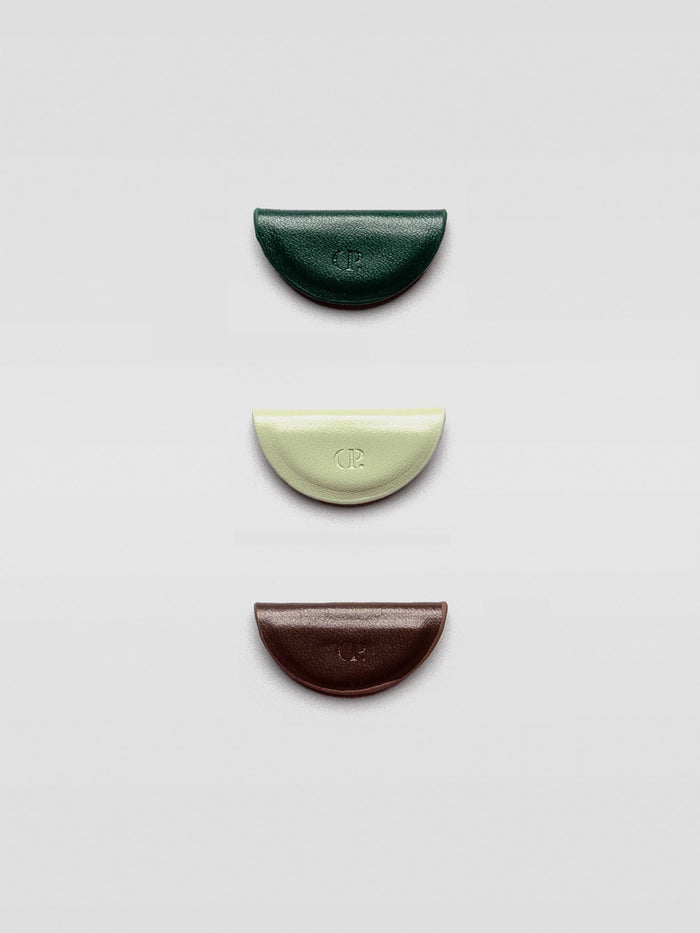 Three half-moon magnetic bookmarks in dark green, pale mint, and deep brown arranged vertically