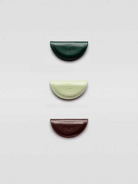 Three half-moon magnetic bookmarks in dark green, pale mint, and deep brown arranged vertically