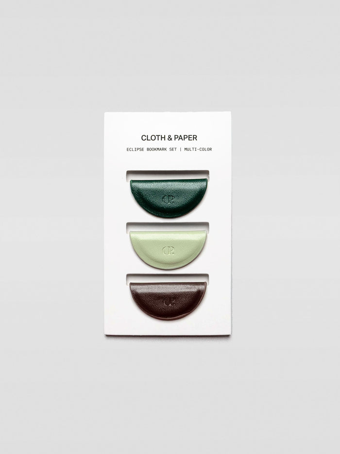 Three half-moon magnetic bookmarks in dark green, pale mint, and deep brown arranged vertically on a white Cloth & Paper branded backing card.
