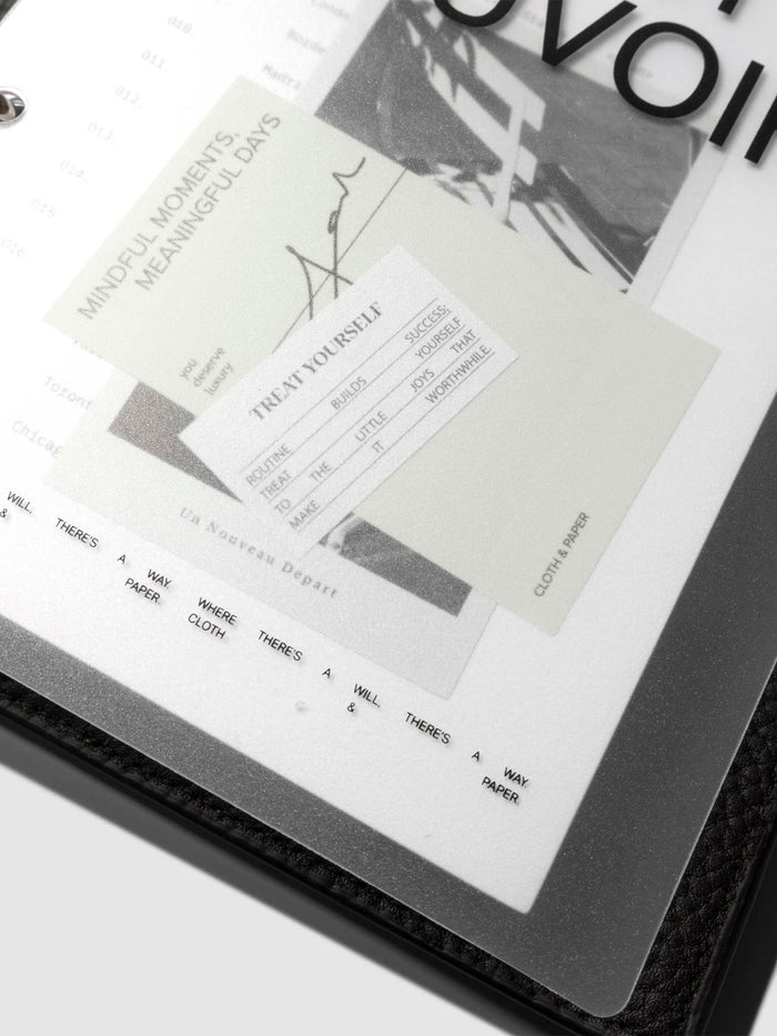 Close up image of the bottom half of the Moments Cover and Dashboard displayed in a black agenda with silver rings. It is turned at a slight angle on a neutral background.