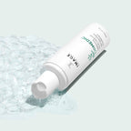 ORMEDIC® balancing facial cleanser | IMAGE Skincare bottle lying on its side with clear foam bubbles and a drop of cleanser on a light background, showcasing skincare and wellness.