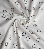 White satin nightwear fabric with black smiley faces, soft drape