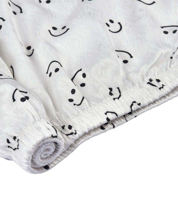 White pajama shorts hem with elastic edge and black lace trim, smiley print