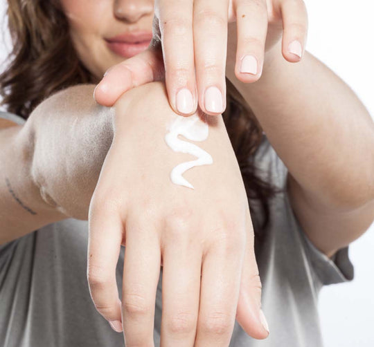 Person applying white cream on the back of their hand, demonstrating use of Sugar Moon Dip® Hands | Farmhouse Fresh skincare product for hand care and wellness.
