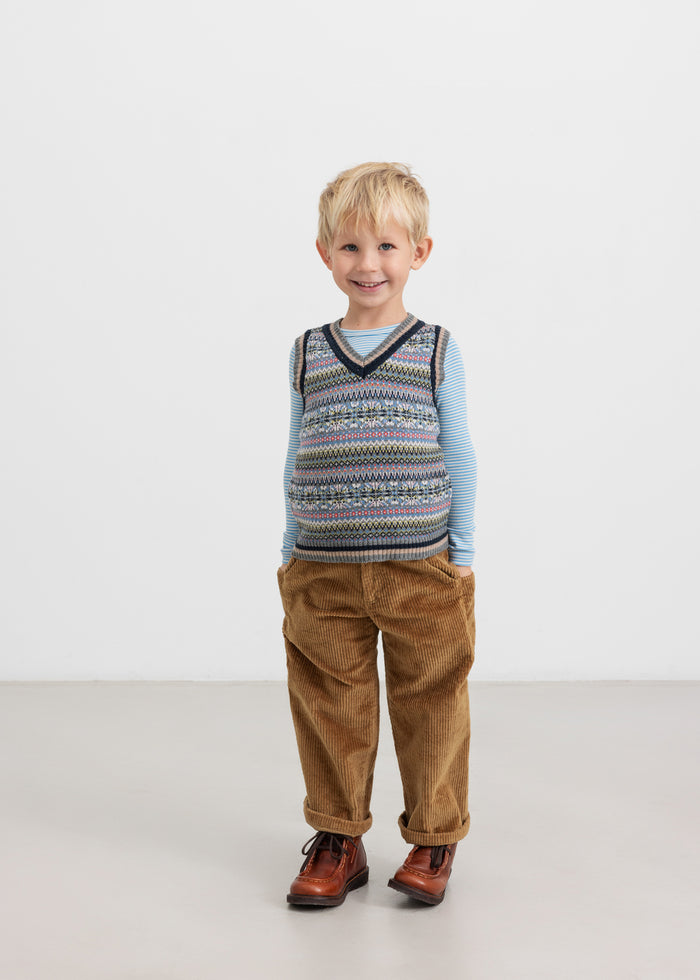 Boy in brown pants and colorful knitted vest with V-neck