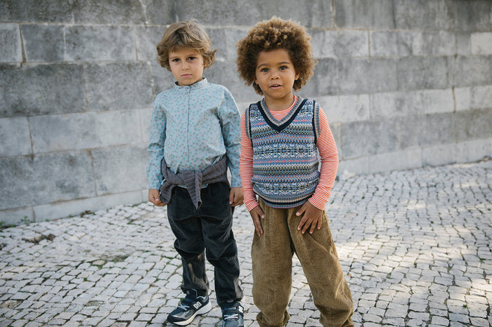 Two boys playing outdoors, one wearing a knitted vest