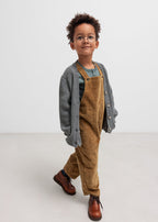 Boy in brown suspenders and gray cardigan