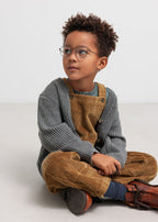 Boy in brown suspenders and gray cardigan