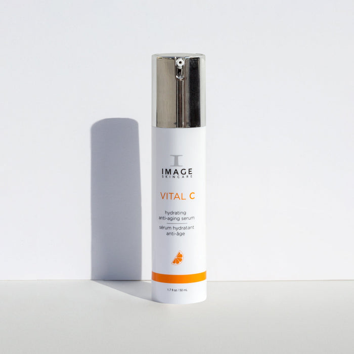Bottle of VITAL C hydrating anti-aging serum | IMAGE Skincare standing upright with a silver pump dispenser casting a shadow on a white background, highlighting skincare and wellness.