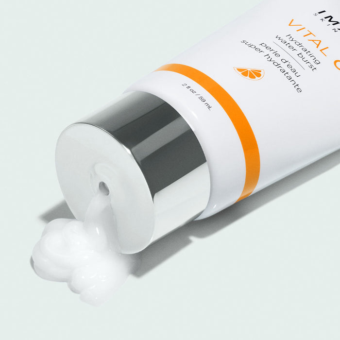 Tube of VITAL C hydrating water burst | IMAGE Skincare with white cream emerging from the silver-capped nozzle on a pale background, showcasing skincare product texture.